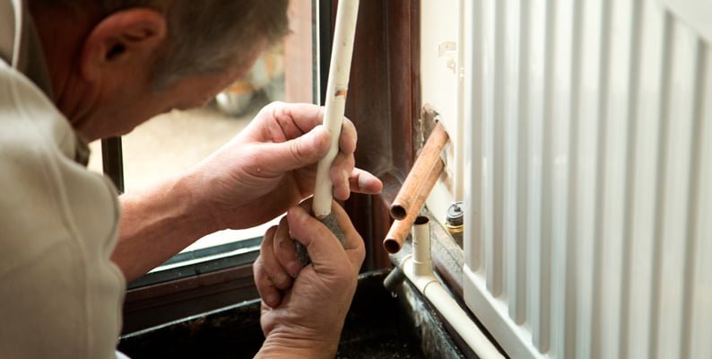 man fixing radiator pipes